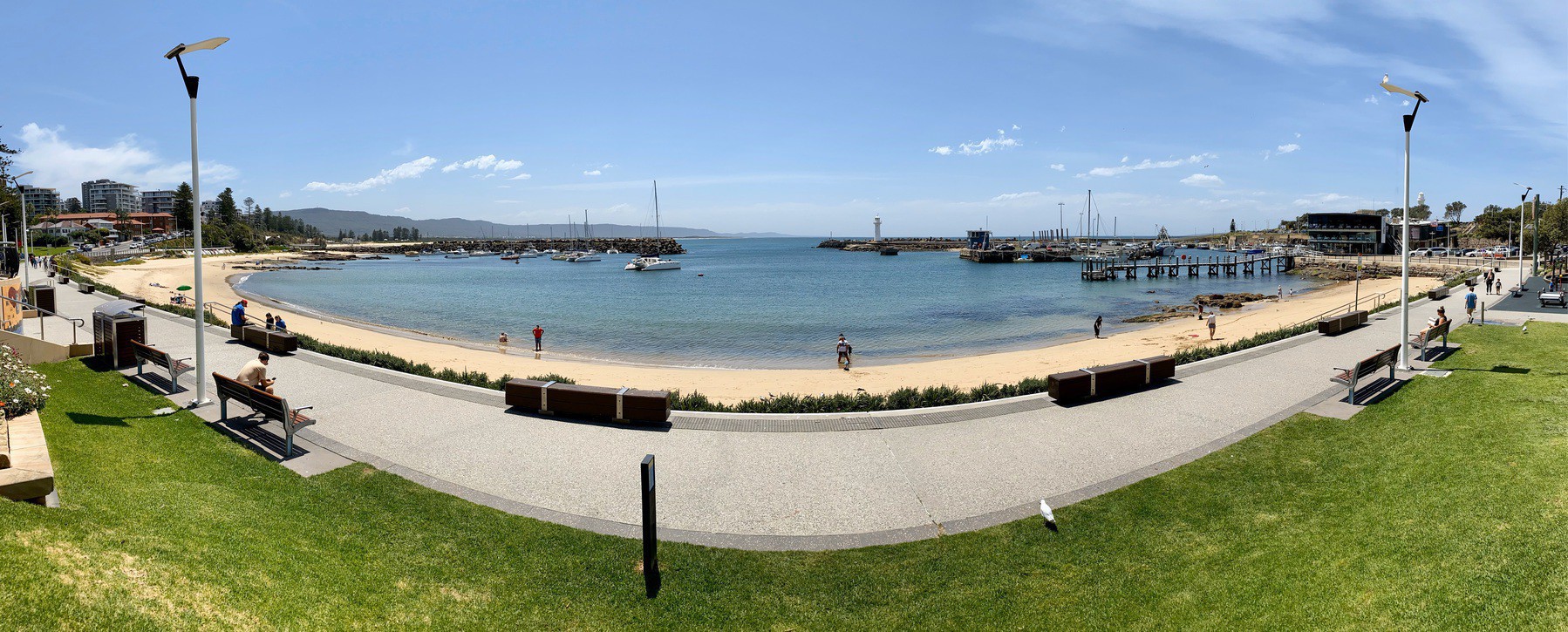 Panorama of a sunny day over the water, footpath and sand