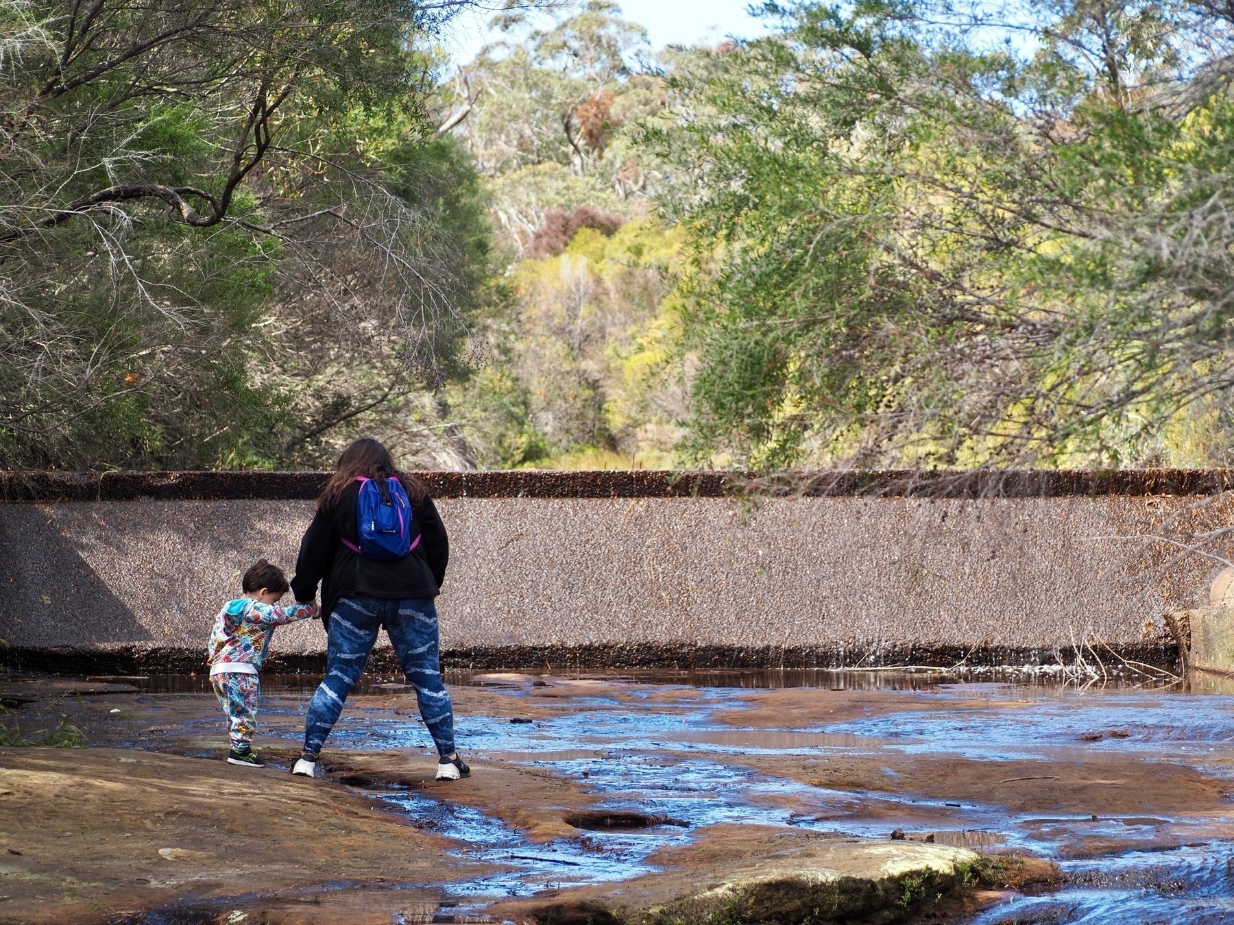 A mother and son navigate rock pools in a national park.
