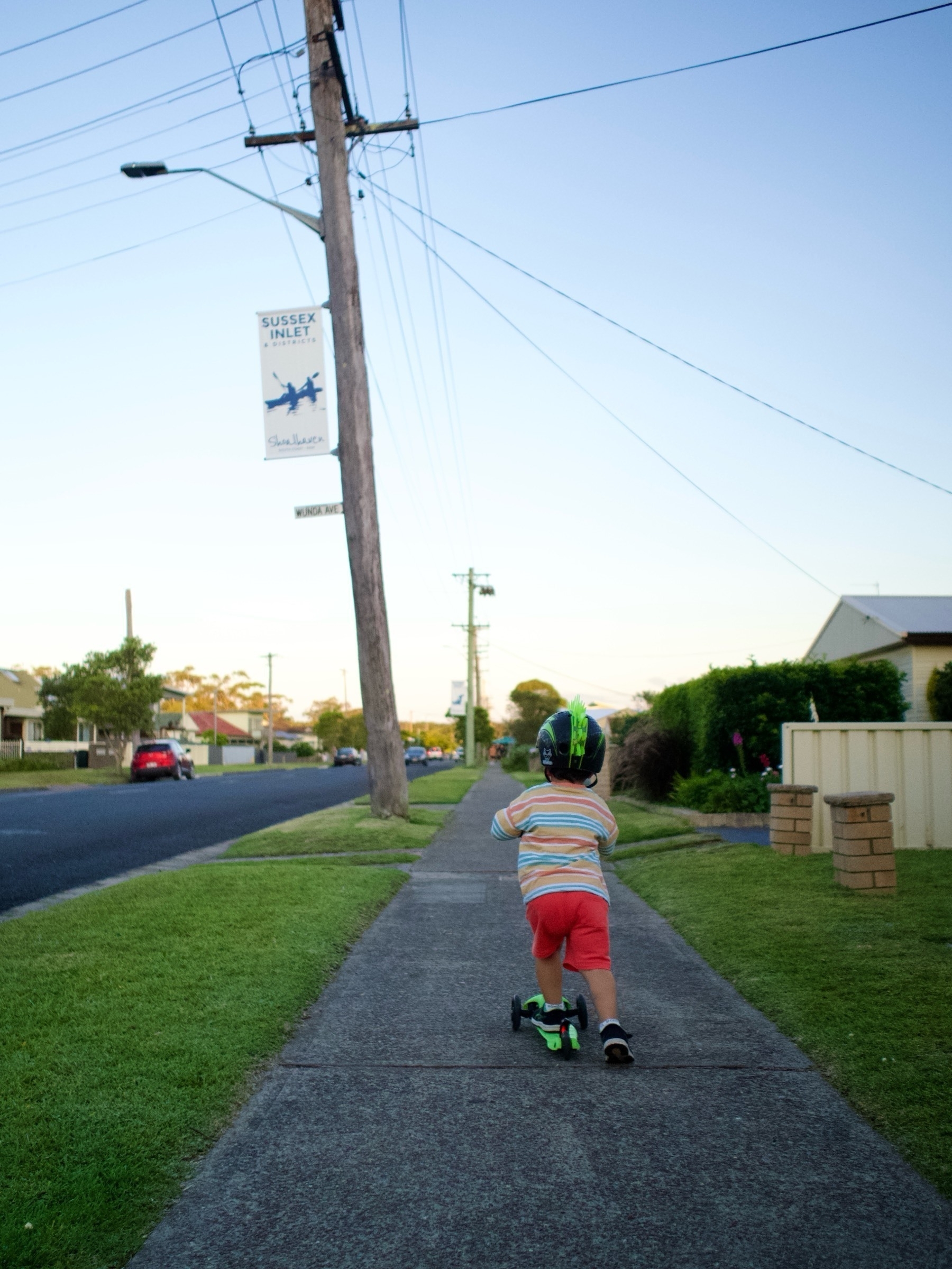 A toddler riding a scooter on a footpath