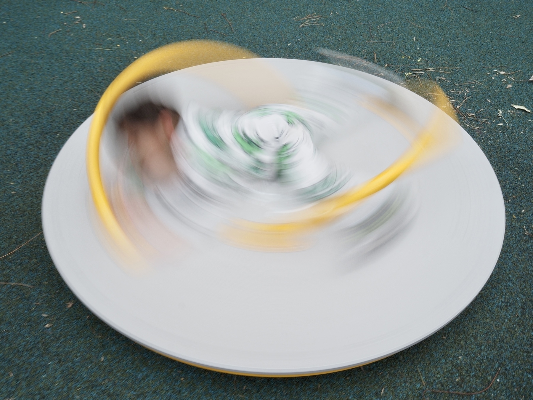 A long-exposure shot of a kid spinning on a piece of playground equipment
