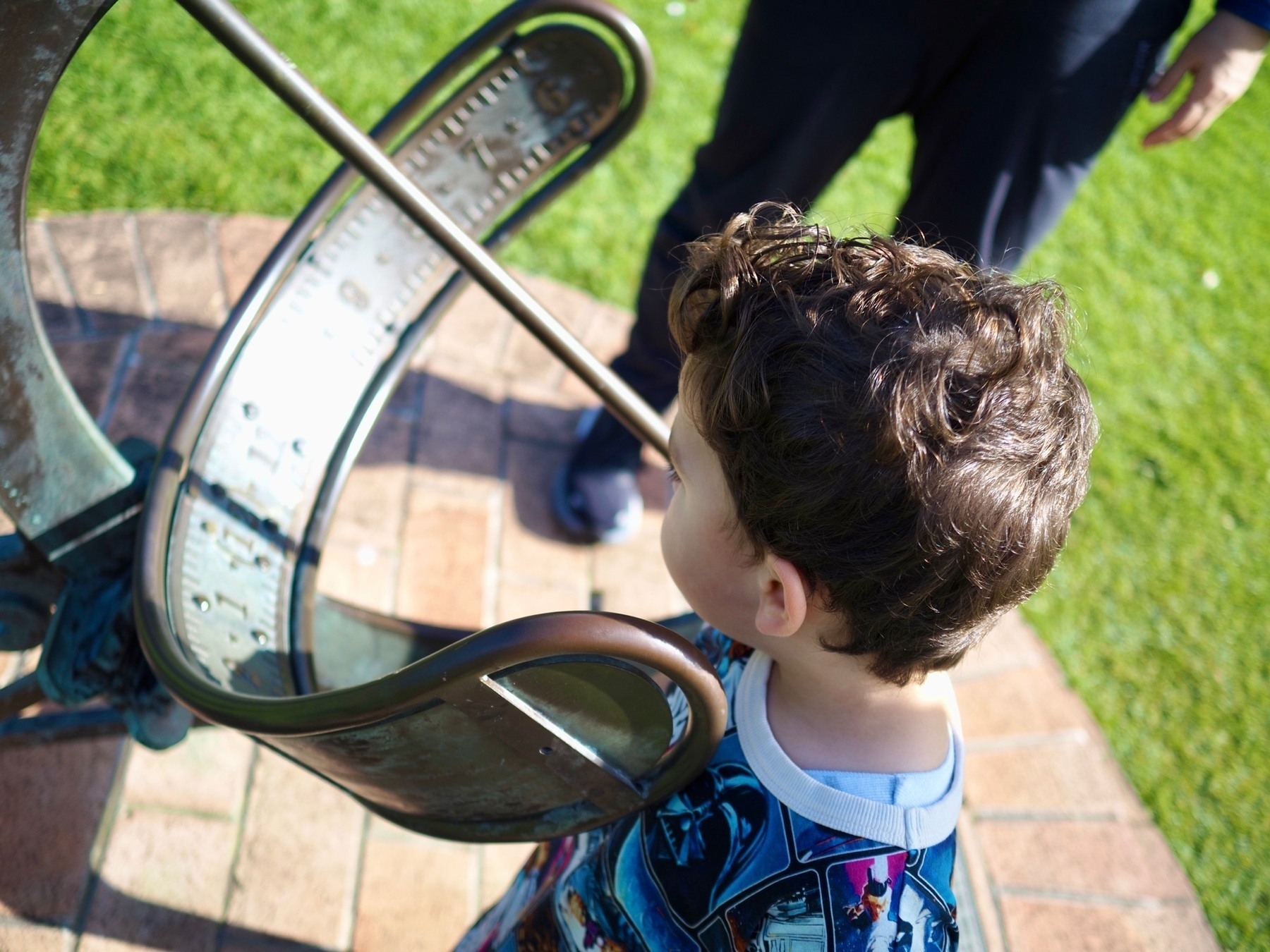 Boy looks at a sundial of sorts
