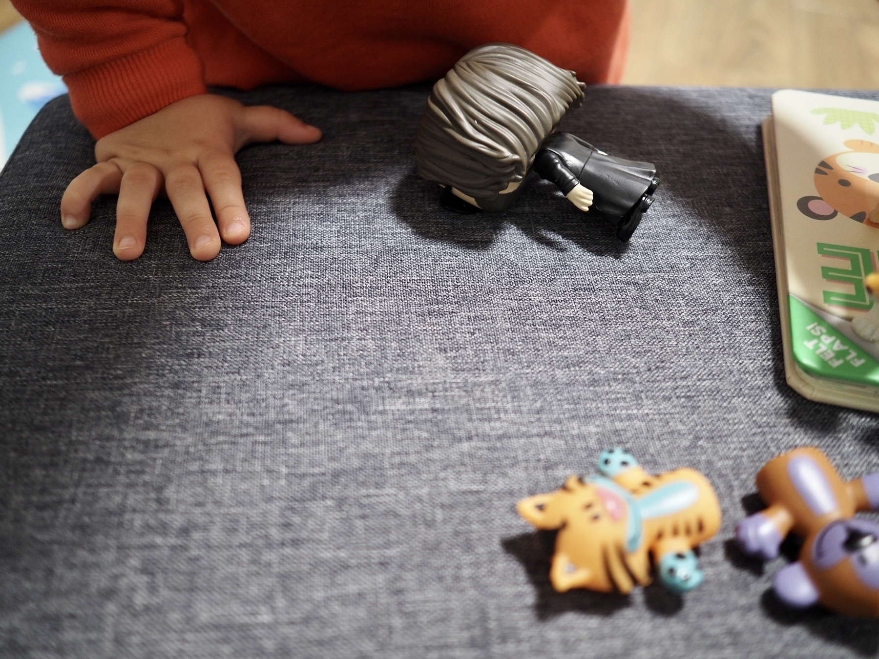 A toddler’s hand next to toys on a footrest