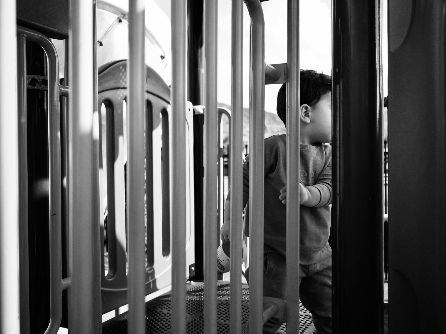 Black-and-white image of an obscured toddler on play equipment