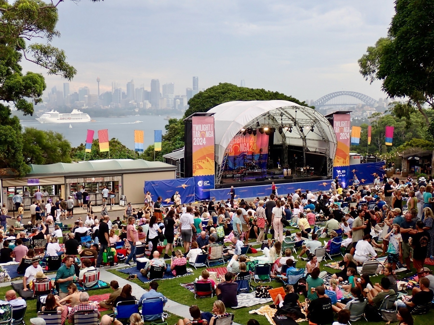 Looking over a crowd of people waiting for a concert, with a stage and the city of Sydney in the background