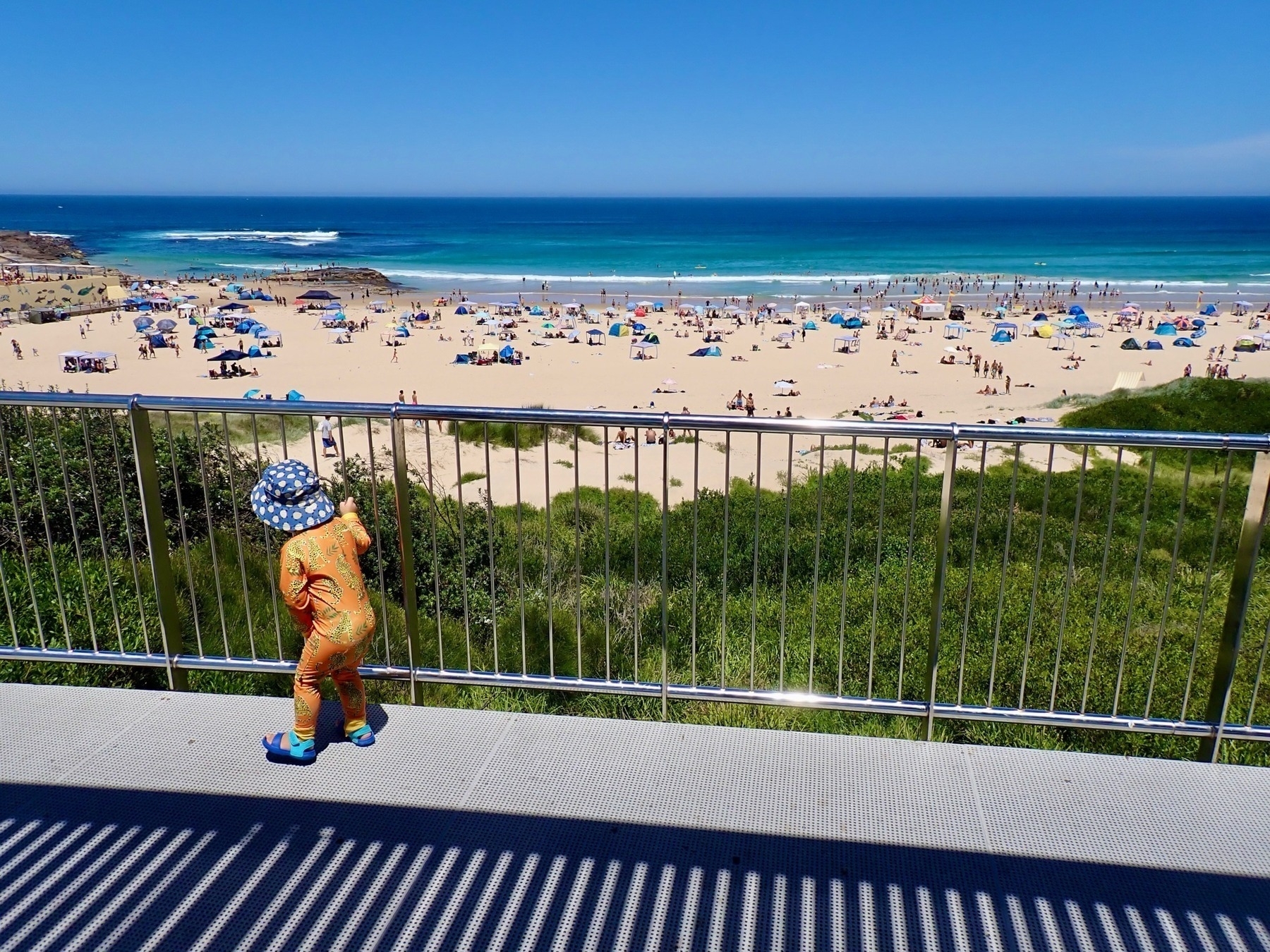 Overlooking Port Kembla Beach and the Tasman Sea from a viewing platform, with a toddler in the foreground