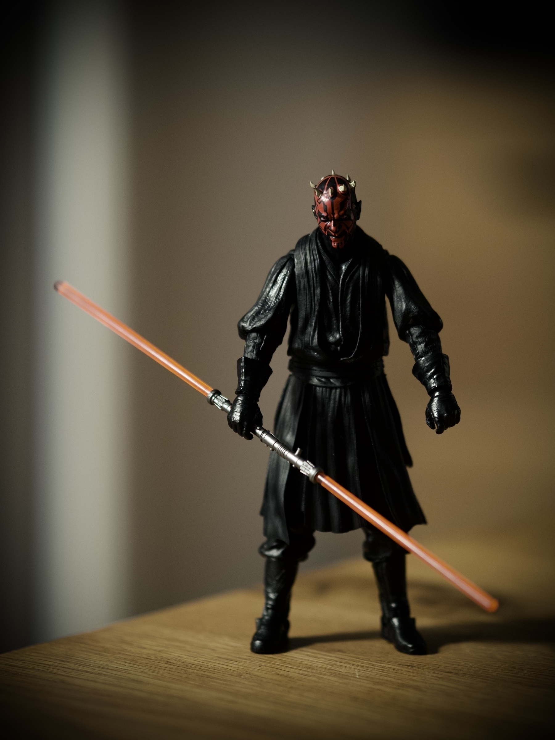 A Darth Maul figurine with a double-bladed lightsabre standing on the edge of a table
