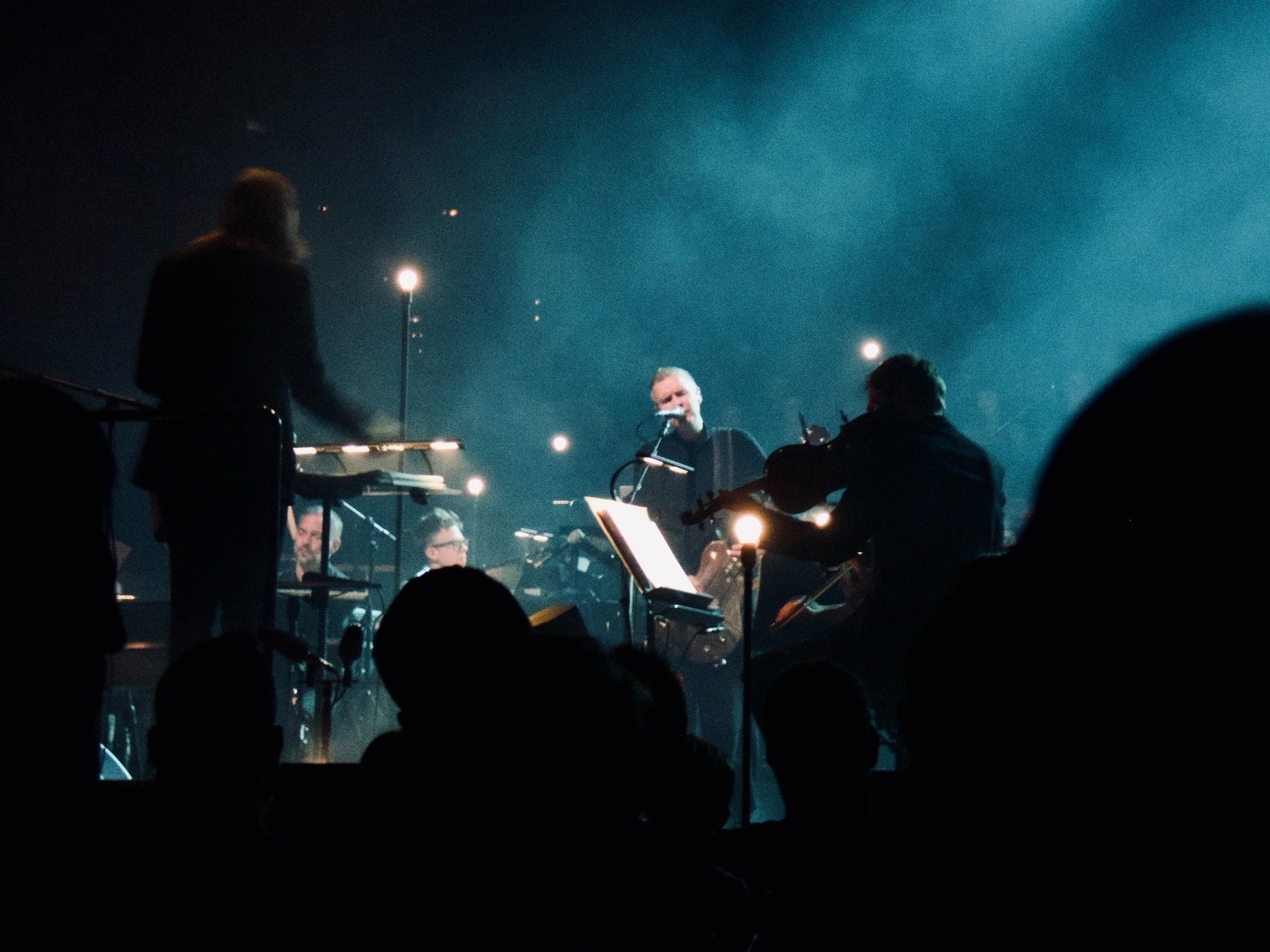 Jónsi performs 'Ekki múkk', framed between the conductor and a violinist.