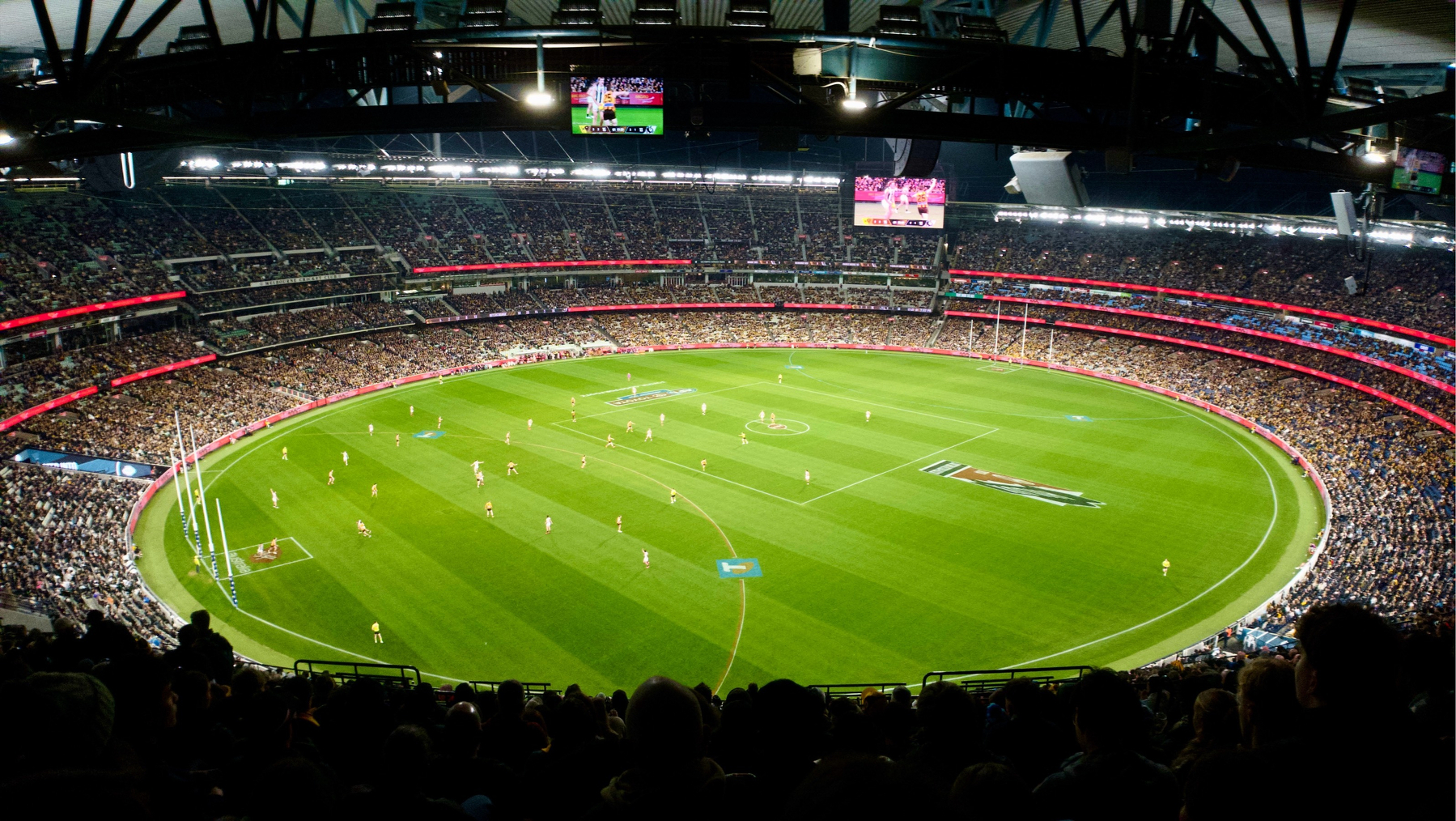 Anamorphic shot of the MCG with a packed crowd watching an AFL match